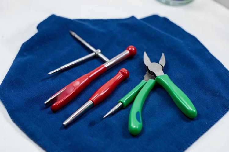 Um conjunto de ferramentas de reparo, incluindo chaves de fenda e alicates, organizadas sobre um pano azul.
